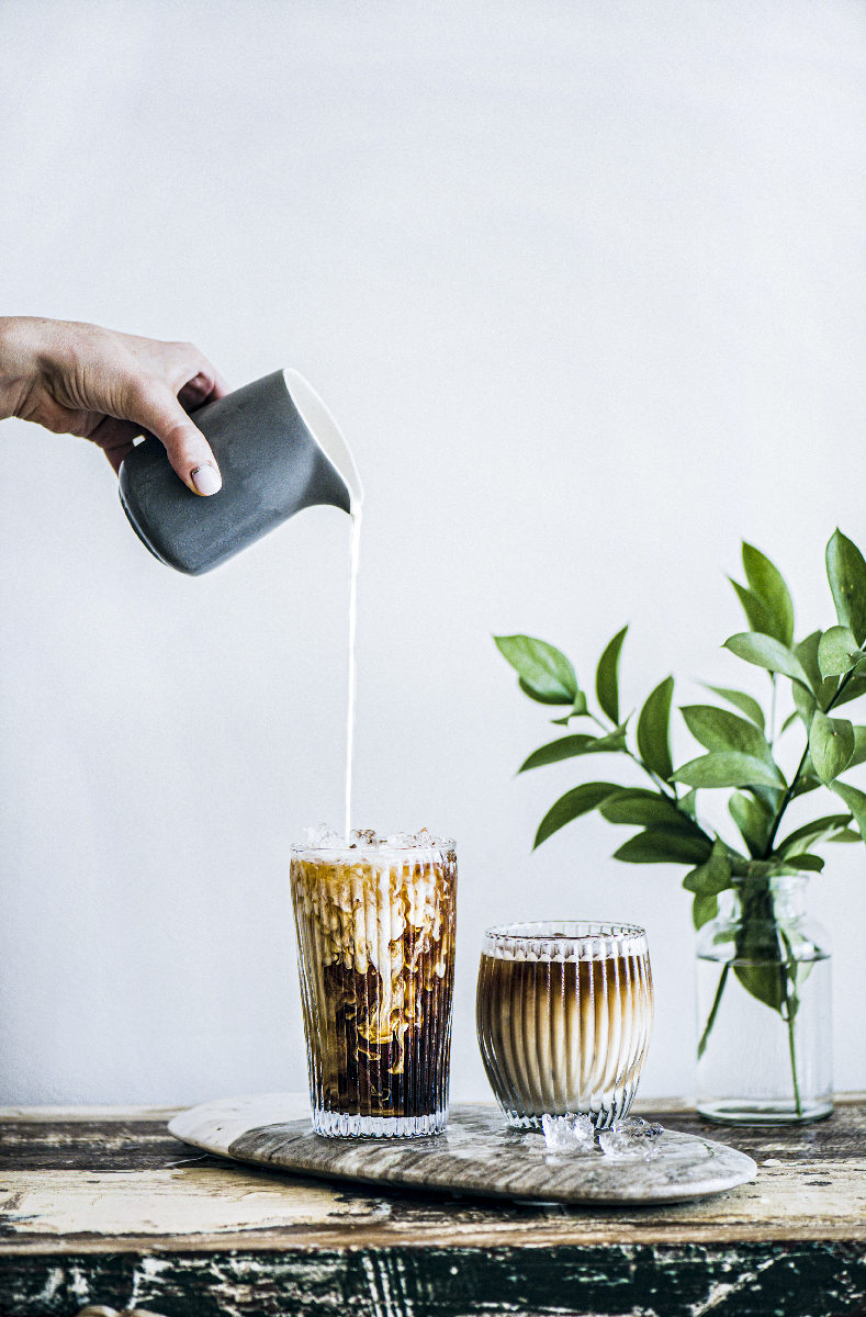 Iced coffee in a tall glass with cream poured over